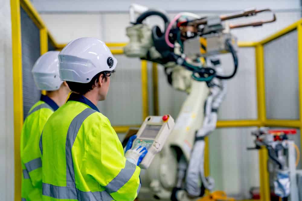 Engineers controlling a robotic arm machine that uses flex PCBs