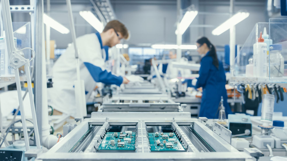 Workers assembling a circuit board in a factory